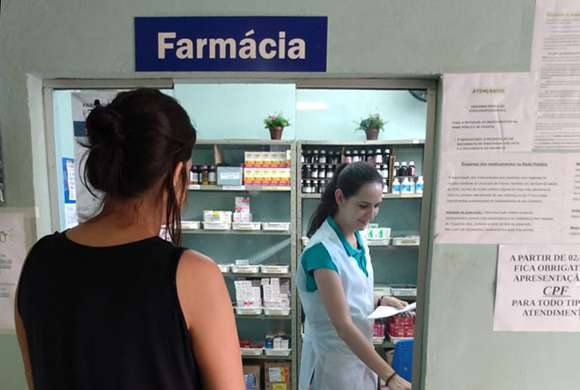 Paciente sendo atendida num guichê de farmácia de unidade de saúde de Franca
