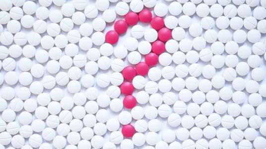 Muitos comprimidos brancos espalhados e ao centro um ponto de interrogação pink formado por comprimidos